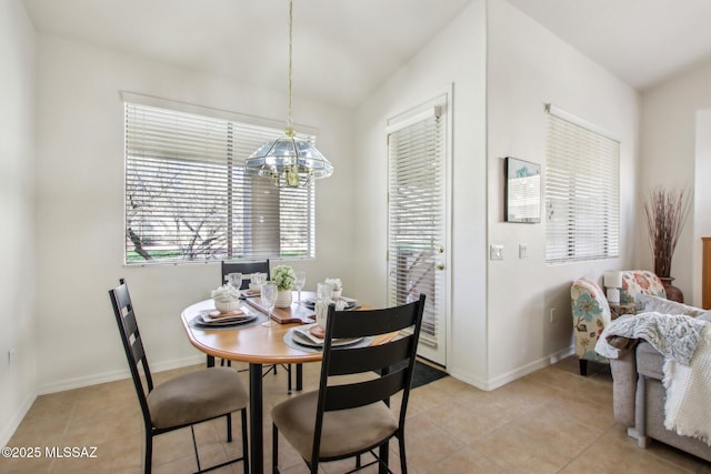 dining space with vaulted ceiling, light tile patterned floors, and an inviting chandelier