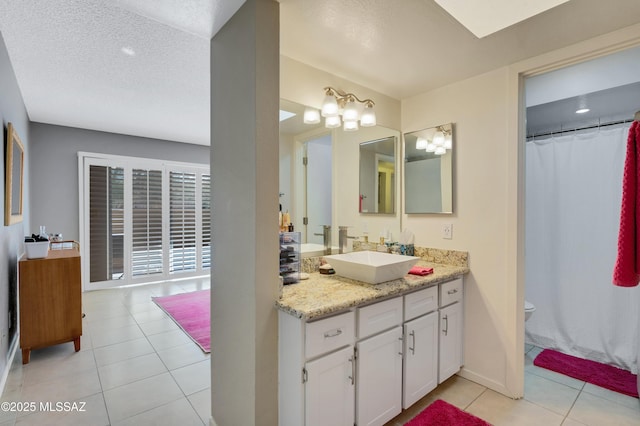 bathroom with vanity, a textured ceiling, toilet, and tile patterned flooring