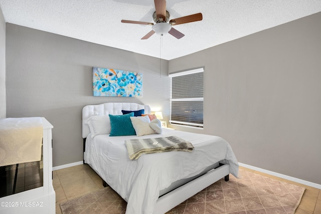 tiled bedroom with ceiling fan and a textured ceiling