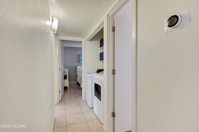 hall with washer and clothes dryer and light tile patterned floors