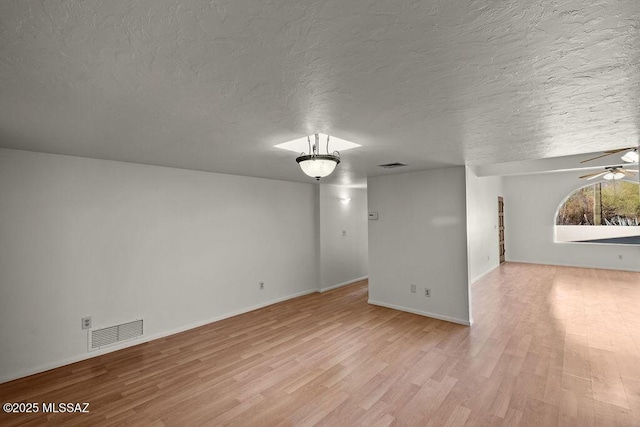 spare room featuring light hardwood / wood-style floors and a textured ceiling