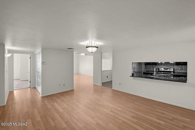 unfurnished living room with sink and light hardwood / wood-style flooring