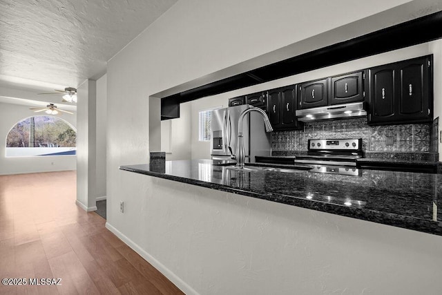 kitchen with backsplash, sink, wood-type flooring, dark stone countertops, and stainless steel electric range