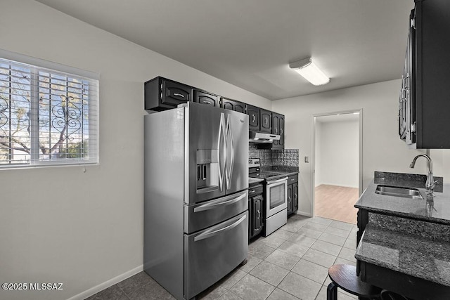 kitchen featuring sink, light tile patterned floors, dark stone counters, and appliances with stainless steel finishes