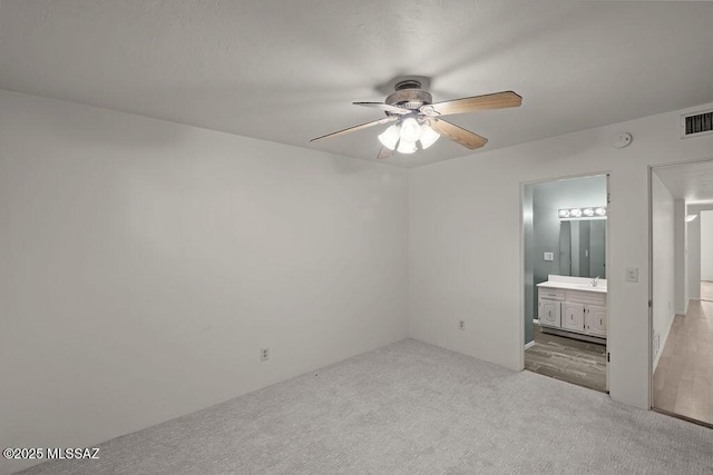 unfurnished bedroom featuring light carpet, connected bathroom, ceiling fan, and sink