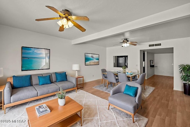 living room with beamed ceiling, hardwood / wood-style floors, and ceiling fan