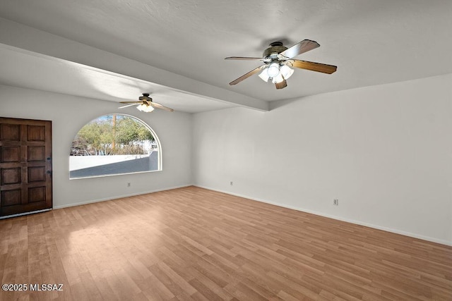 empty room featuring beamed ceiling and light hardwood / wood-style floors