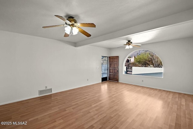 empty room with beamed ceiling and light wood-type flooring