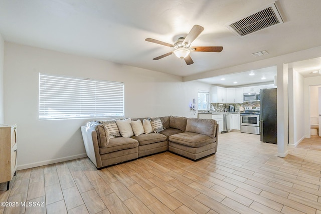 living room with light wood-type flooring and ceiling fan