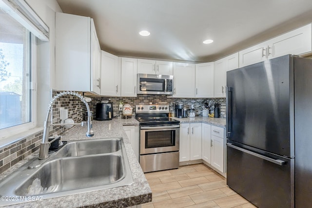 kitchen with sink, decorative backsplash, white cabinetry, and appliances with stainless steel finishes