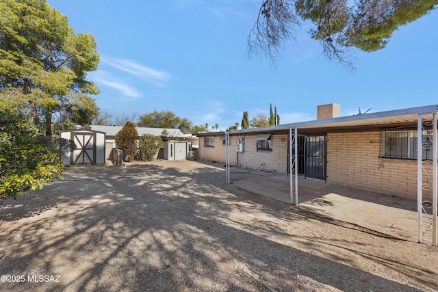 back of property with a storage shed and a patio