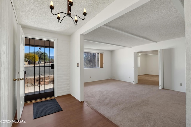 foyer featuring an inviting chandelier, plenty of natural light, carpet, and a textured ceiling