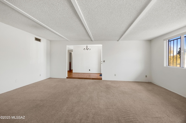 carpeted empty room with a chandelier and a textured ceiling