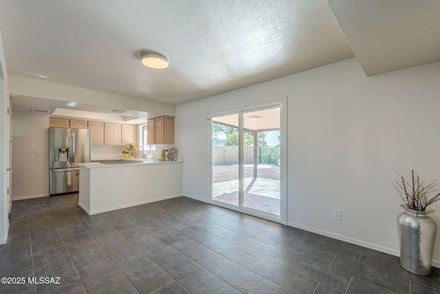 kitchen featuring light brown cabinetry, stainless steel fridge, and kitchen peninsula