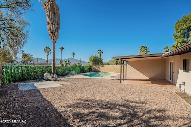 view of yard with a fenced in pool, a mountain view, and a patio area