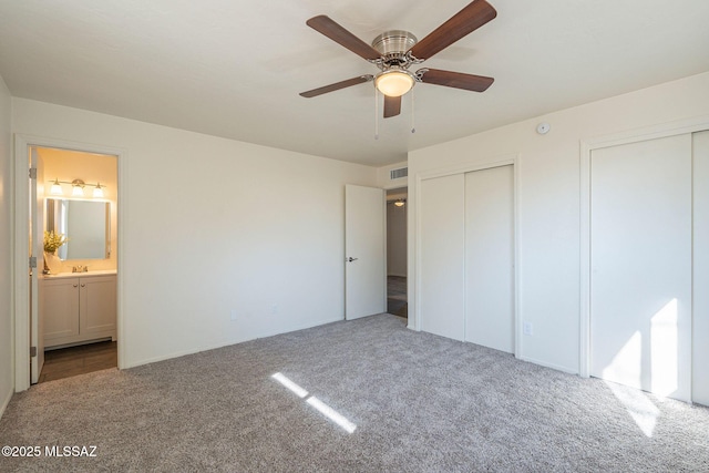 unfurnished bedroom with multiple closets, carpet, and sink