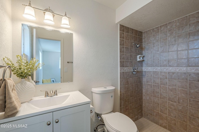 bathroom with vanity, a tile shower, and toilet