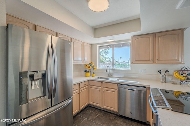 kitchen with sink, light brown cabinets, a tray ceiling, dark tile patterned floors, and stainless steel appliances