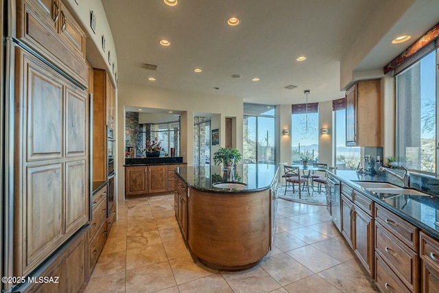 kitchen featuring decorative light fixtures, a kitchen island, plenty of natural light, and sink