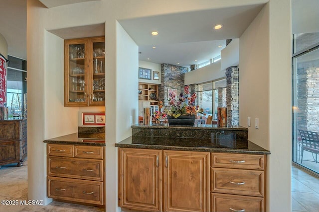 bar featuring dark stone counters and light tile patterned floors