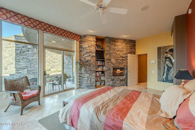 bedroom featuring access to outside, a fireplace, ceiling fan, and multiple windows