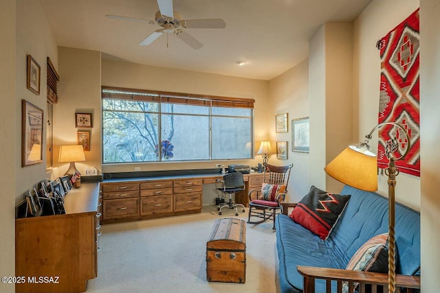 interior space with built in desk, ceiling fan, and light carpet