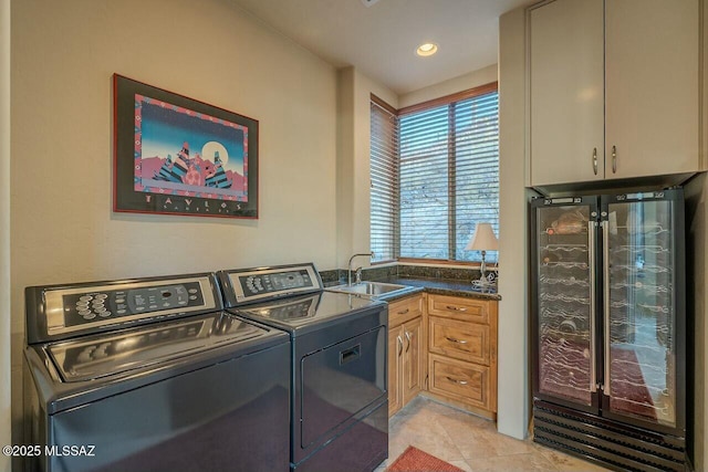 laundry room with sink, light tile patterned floors, cabinets, and independent washer and dryer