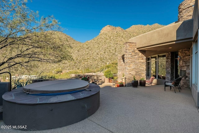 view of patio featuring a hot tub and a mountain view