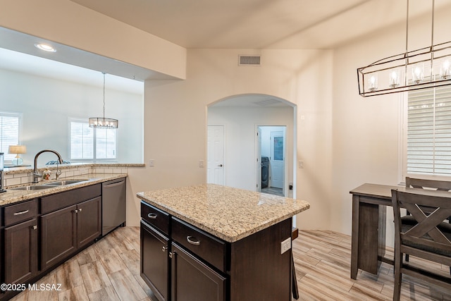 kitchen with sink, stainless steel dishwasher, hanging light fixtures, and a center island