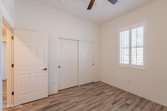 unfurnished bedroom with ceiling fan, light wood finished floors, and a closet