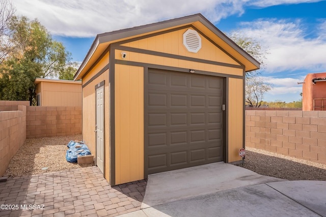detached garage with concrete driveway and fence