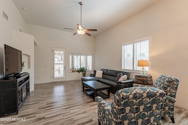 living room with high vaulted ceiling, ceiling fan, and light wood-type flooring