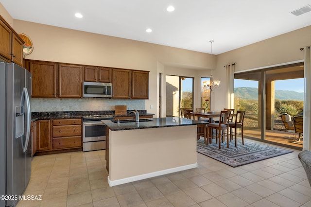 kitchen featuring appliances with stainless steel finishes, an island with sink, sink, a notable chandelier, and a mountain view