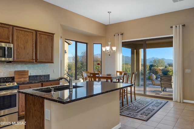 kitchen with sink, decorative light fixtures, dark stone countertops, a mountain view, and stainless steel appliances