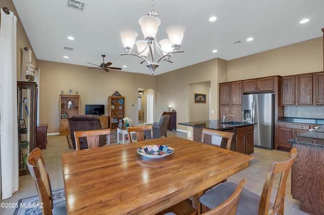 tiled dining area featuring sink and ceiling fan with notable chandelier