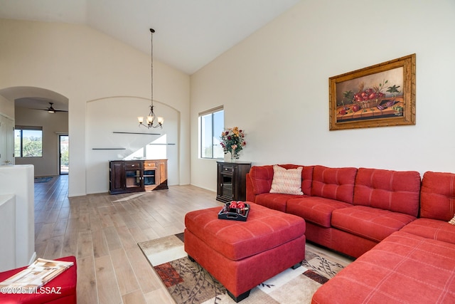 living room with high vaulted ceiling, hardwood / wood-style floors, and an inviting chandelier