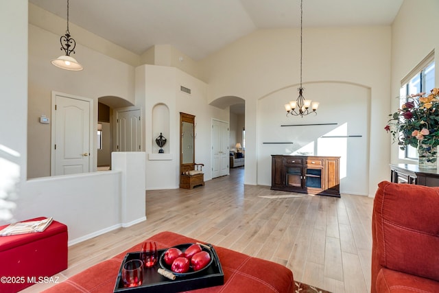 living room featuring a notable chandelier, high vaulted ceiling, and wood-type flooring