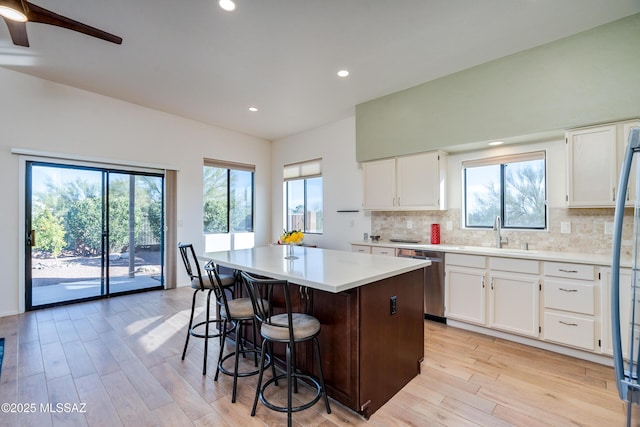 kitchen with white cabinets, stainless steel dishwasher, a center island, and sink