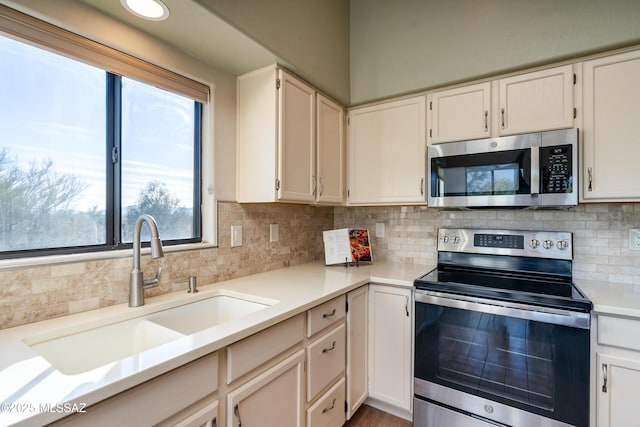 kitchen featuring sink, a wealth of natural light, appliances with stainless steel finishes, and white cabinetry