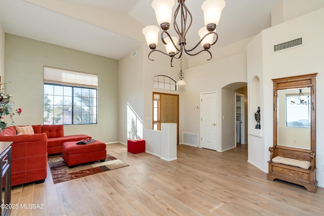 living room with vaulted ceiling, an inviting chandelier, and light hardwood / wood-style floors