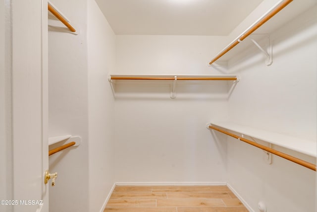 walk in closet with light hardwood / wood-style floors