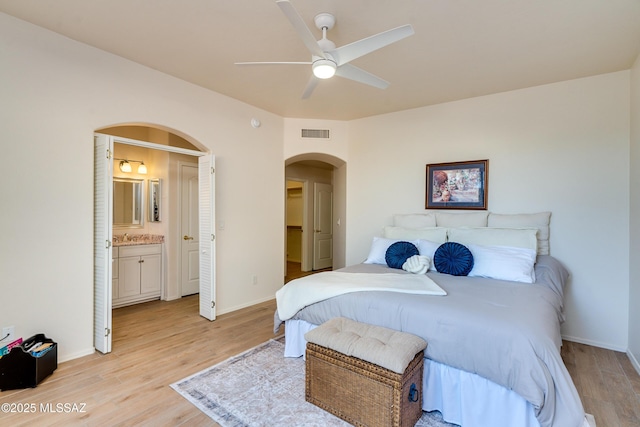 bedroom with light wood-type flooring, ensuite bath, and ceiling fan