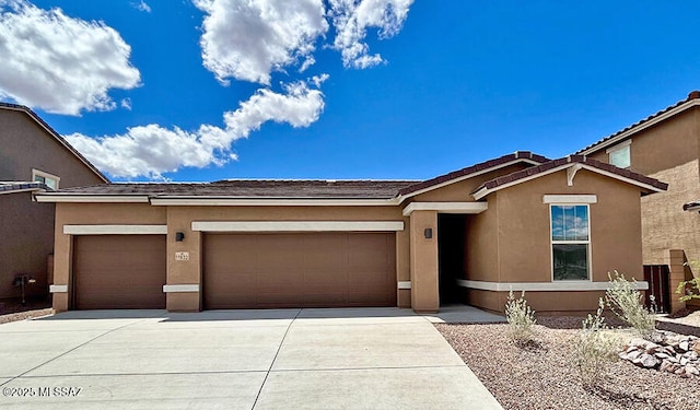 view of front of property featuring a tile roof, an attached garage, driveway, and stucco siding