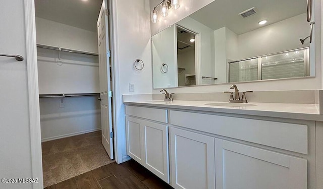 full bath with wood finished floors, visible vents, an enclosed shower, and a sink