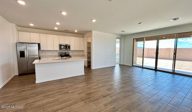 kitchen with white cabinets, stainless steel appliances, baseboards, visible vents, and light countertops