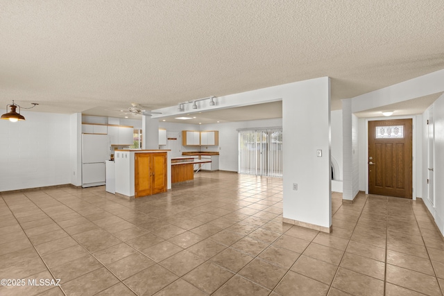 kitchen featuring white refrigerator, a healthy amount of sunlight, kitchen peninsula, and light tile patterned flooring