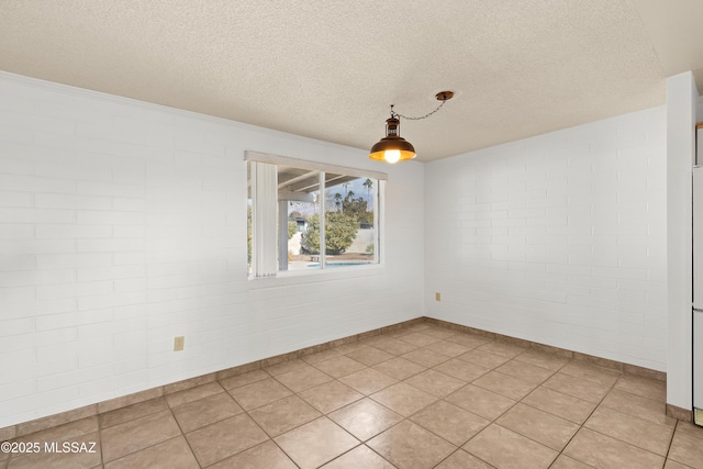 tiled empty room featuring brick wall and a textured ceiling