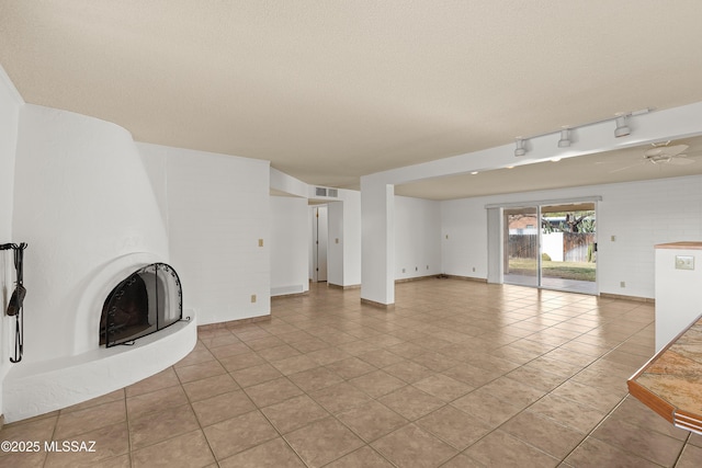 unfurnished living room with light tile patterned flooring, a textured ceiling, and a fireplace