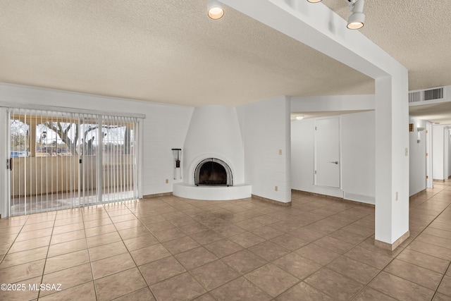 unfurnished living room with light tile patterned floors, a textured ceiling, and a fireplace