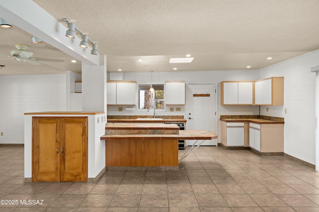 kitchen with sink, white cabinetry, hanging light fixtures, a textured ceiling, and kitchen peninsula